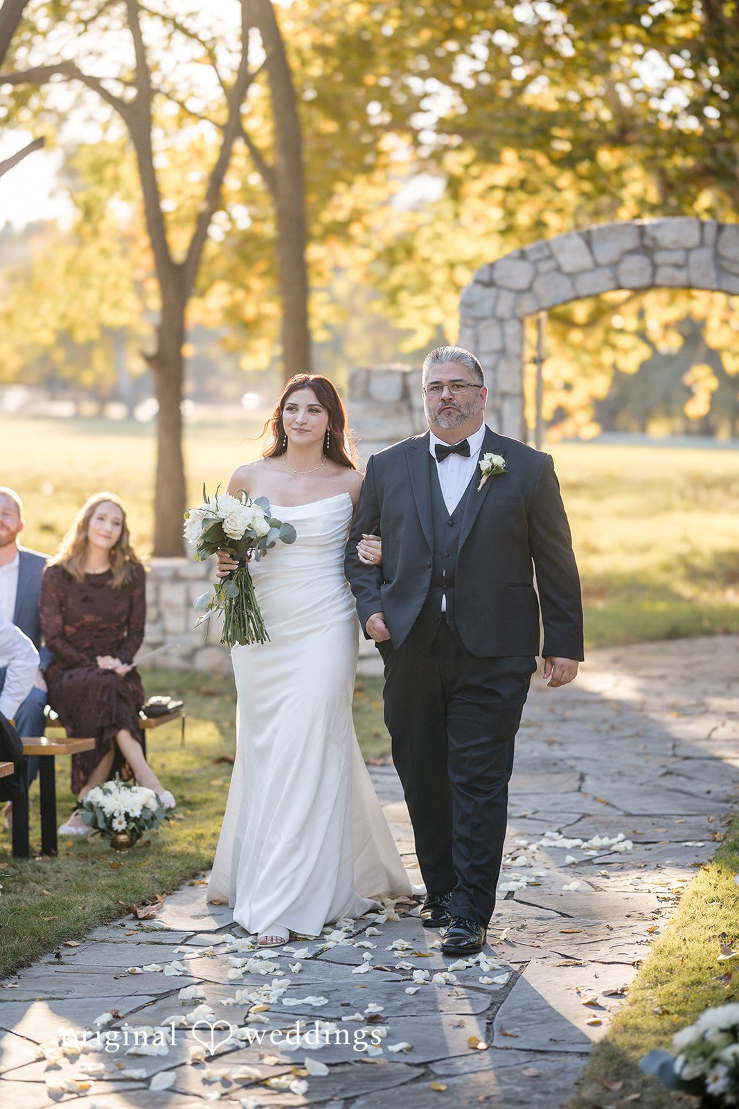 The bride's father walks the bride down the aisle at the River Road wedding ceremony