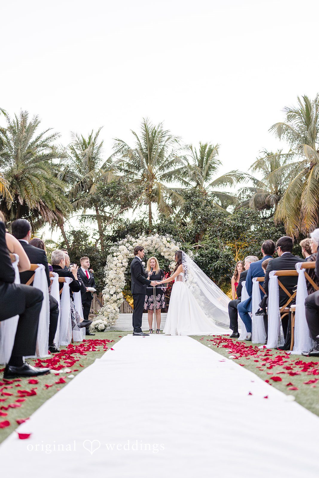 Wide-angle view of a wedding ceremony aisle surrounded by palm trees