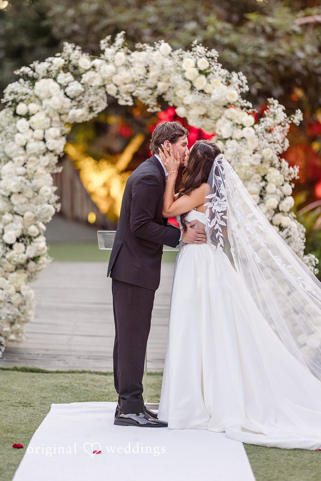 Romantic kiss after the ceremony under a floral arch, Miami Wedding Photography capture