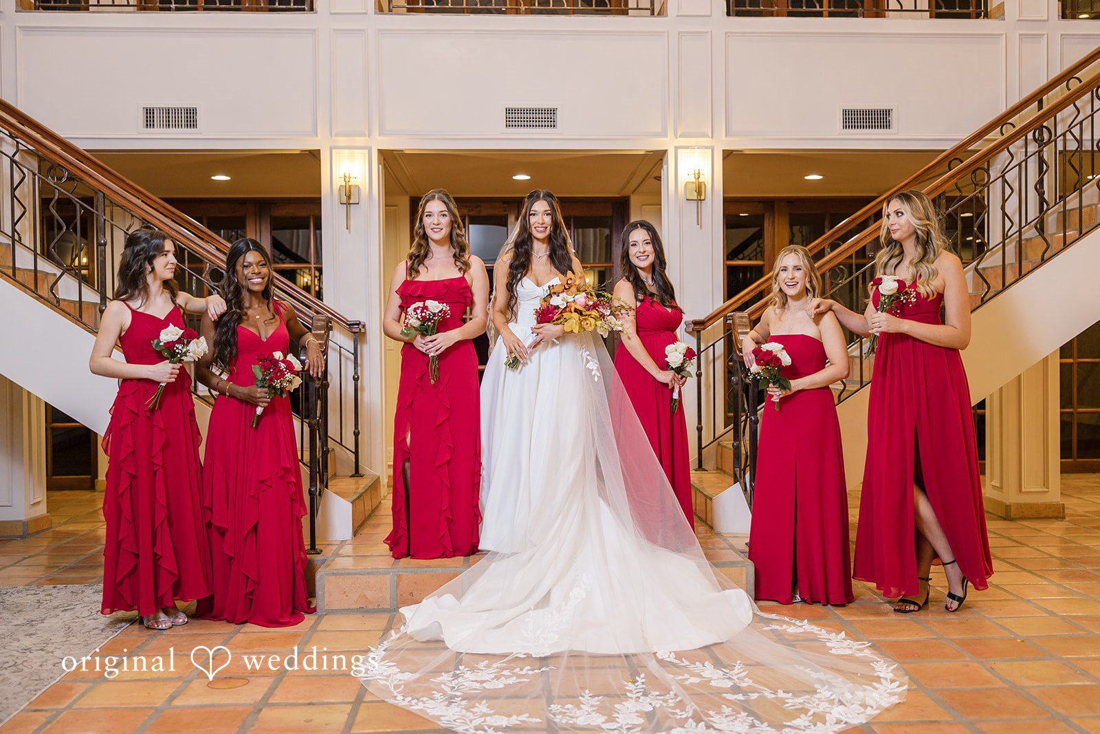 Wedding party portrait with bridesmaids in coordinated red dresses
