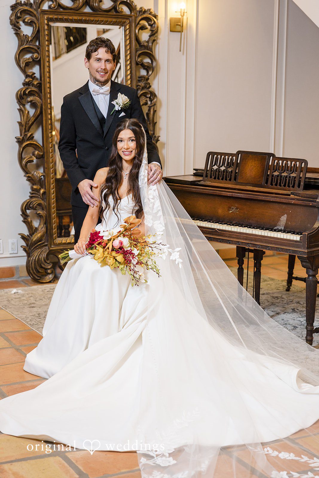 Bride seated indoors holding a bouquet with flowing veil