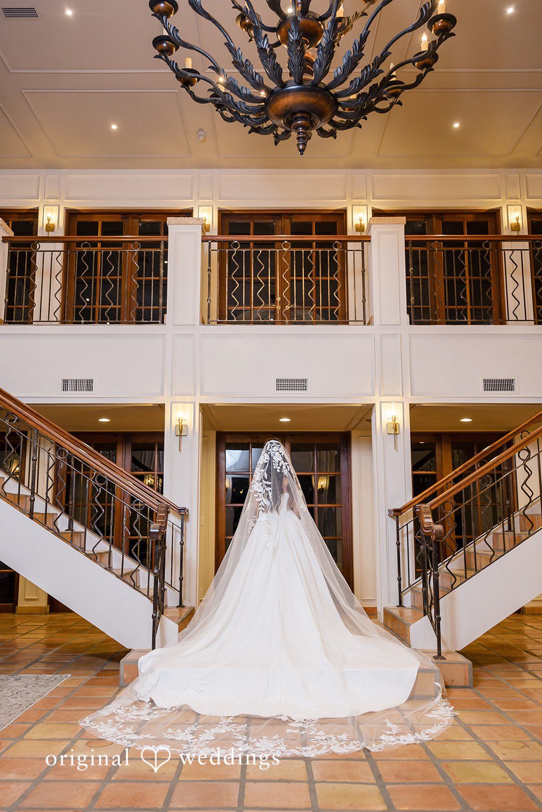 Bride standing alone in a grand hall highlighting the wedding dress train