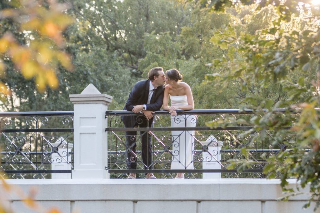 st-louis-wedding-photographer-and-videographer-2 groom kissing bride on bridge in greenery at wedding venues st louis