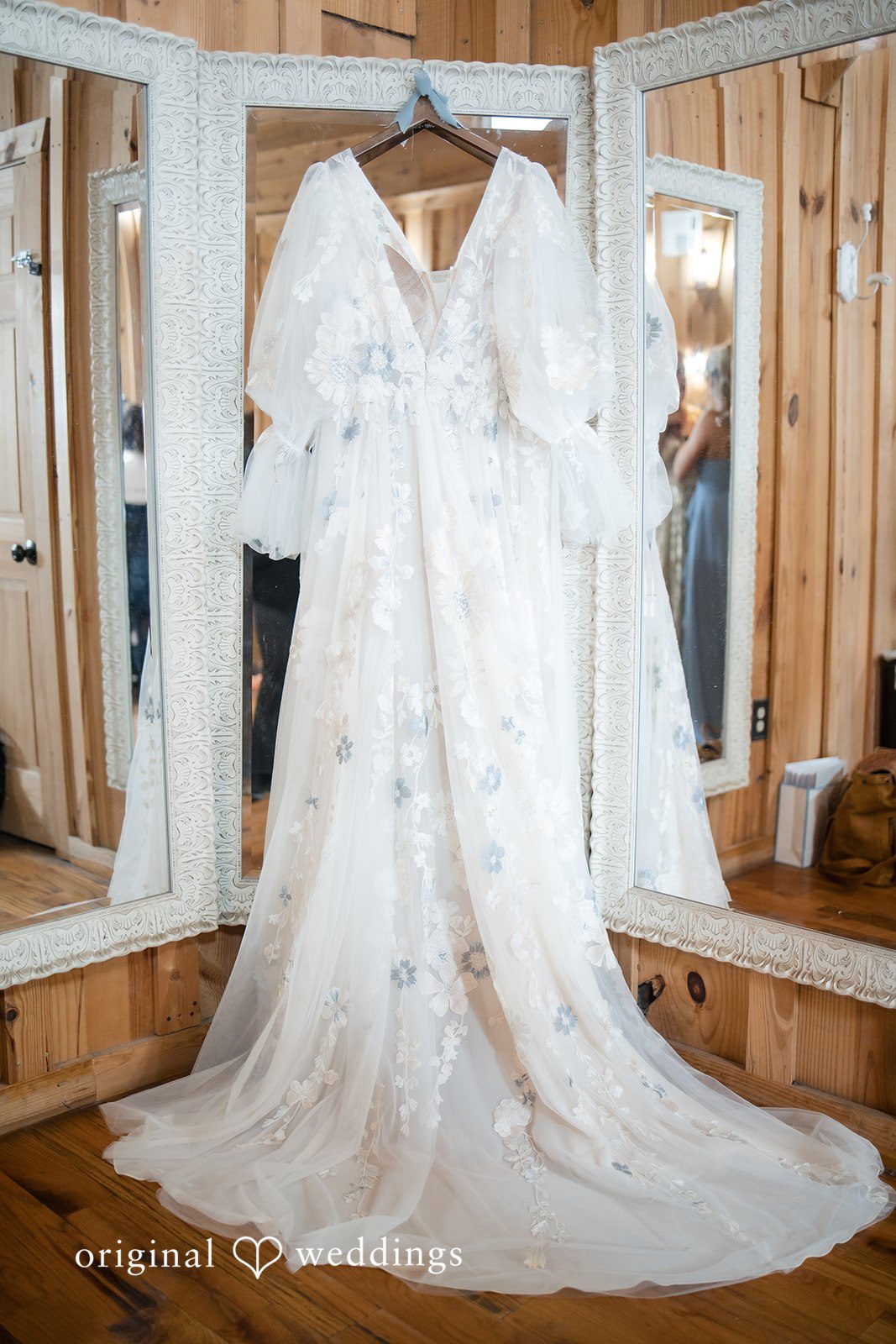 Kelsey + Riley A detailed wedding dress hangs beautifully inside a wooden room.