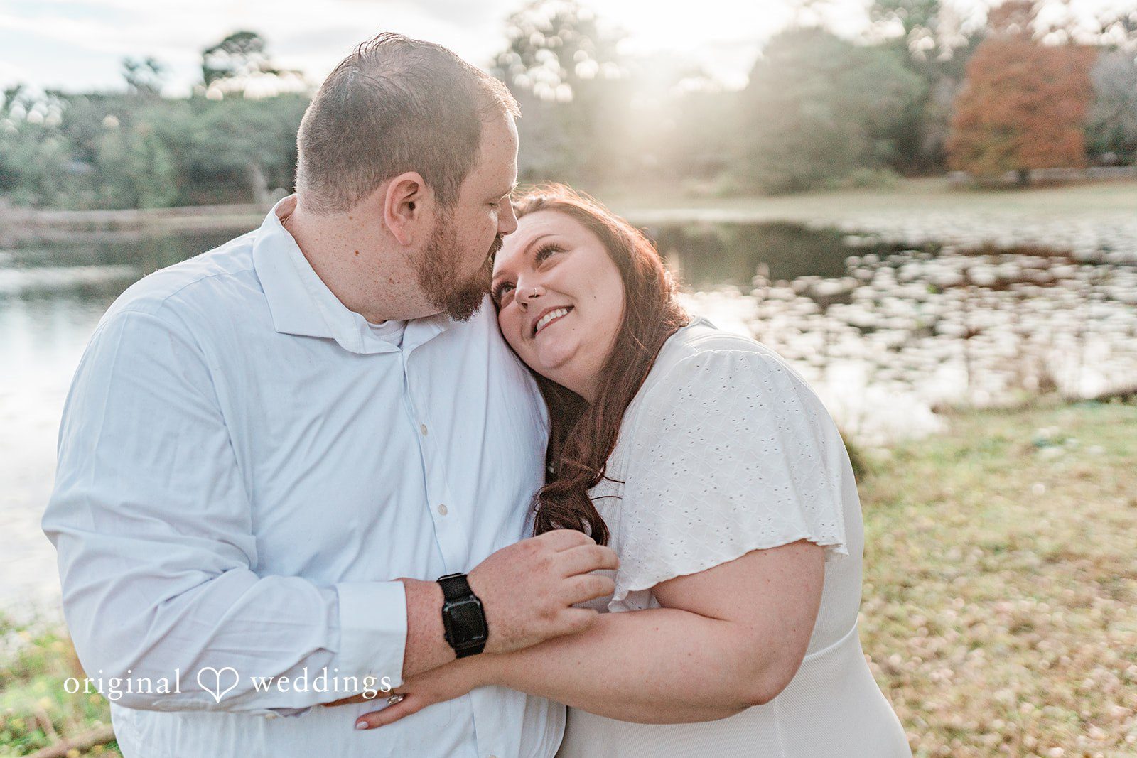 Bride resting her head on groom’s shoulder by the lake side