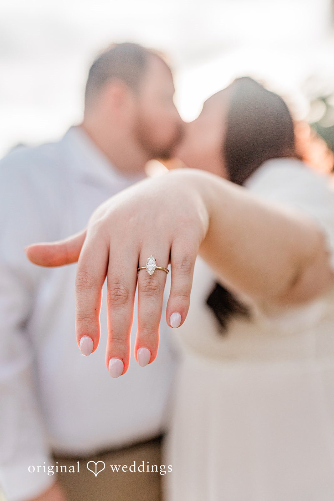 Close-up of engagement ring as couple kisses