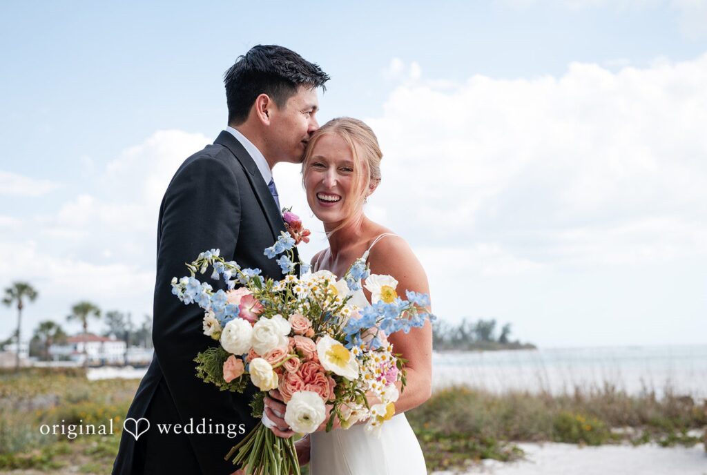 Bride smiling while groom kisses her on the head at The Resort at Longboat Key Club, photographed by Original Weddings