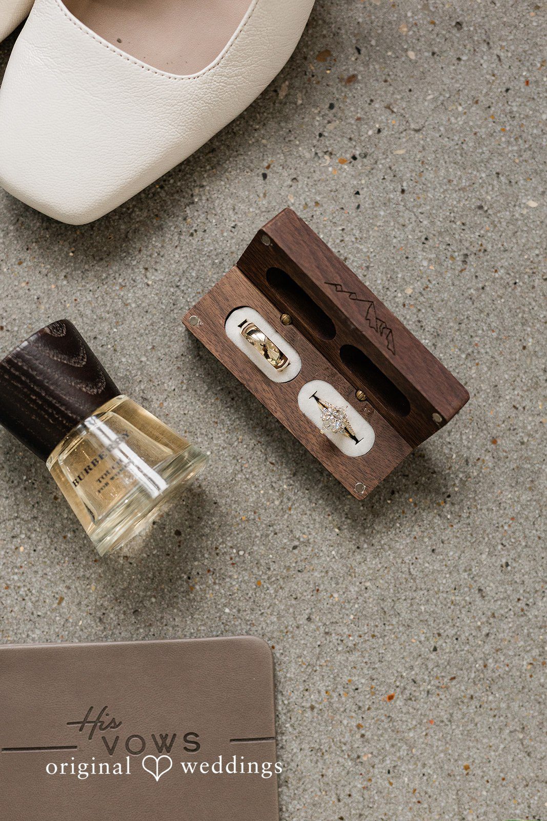 Dominic + Erika Joy A flat-lay arrangement featuring a small glass perfume bottle and two dark wooden boxes holding cufflinks.