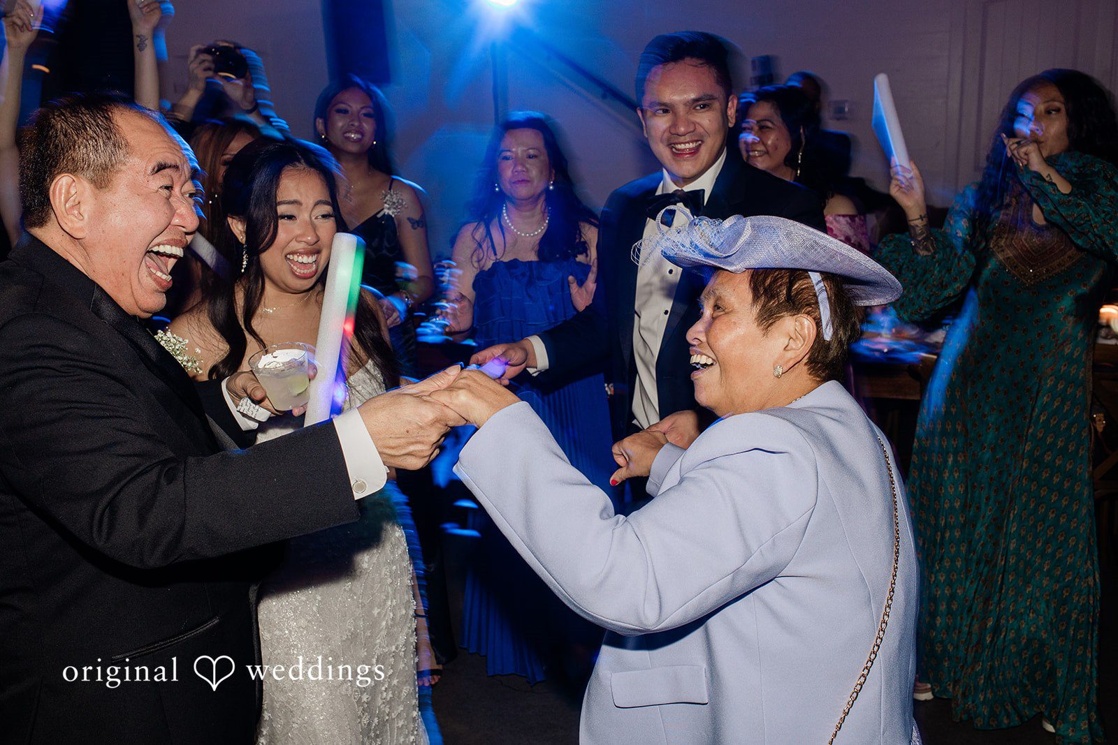 Dominic + Erika Joy A woman in gown laughing and holding hands with a guest during the reception.