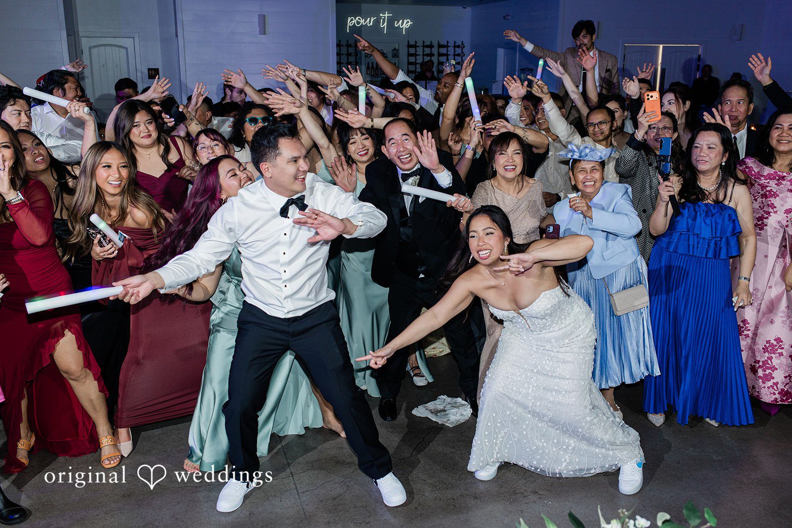 Dominic + Erika Joy Couple in wedding attire dancing energetically with guests at Addison Woods.