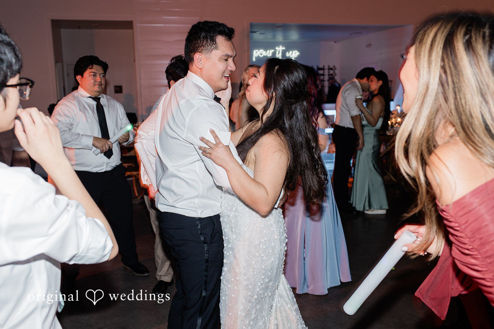 Dominic + Erika Joy Couple in wedding attire sharing a slow dance surrounded by their guests.