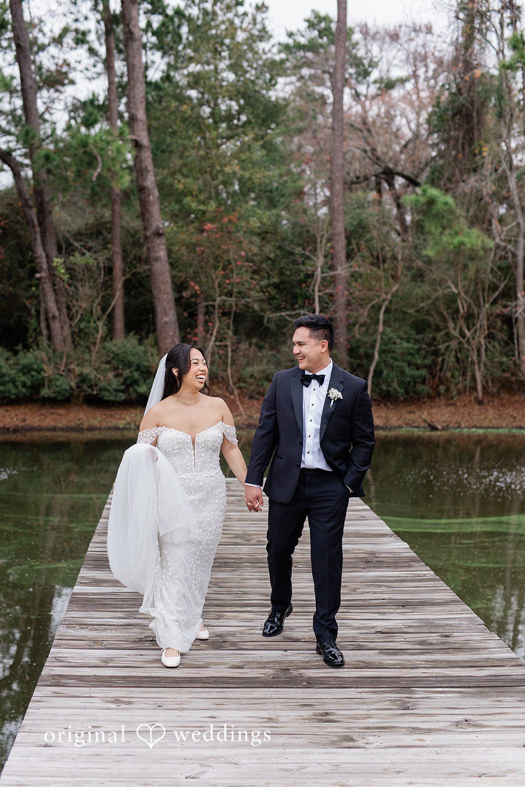 Dominic + Erika Joy Couple walking hand-in-hand down a wooden pier.