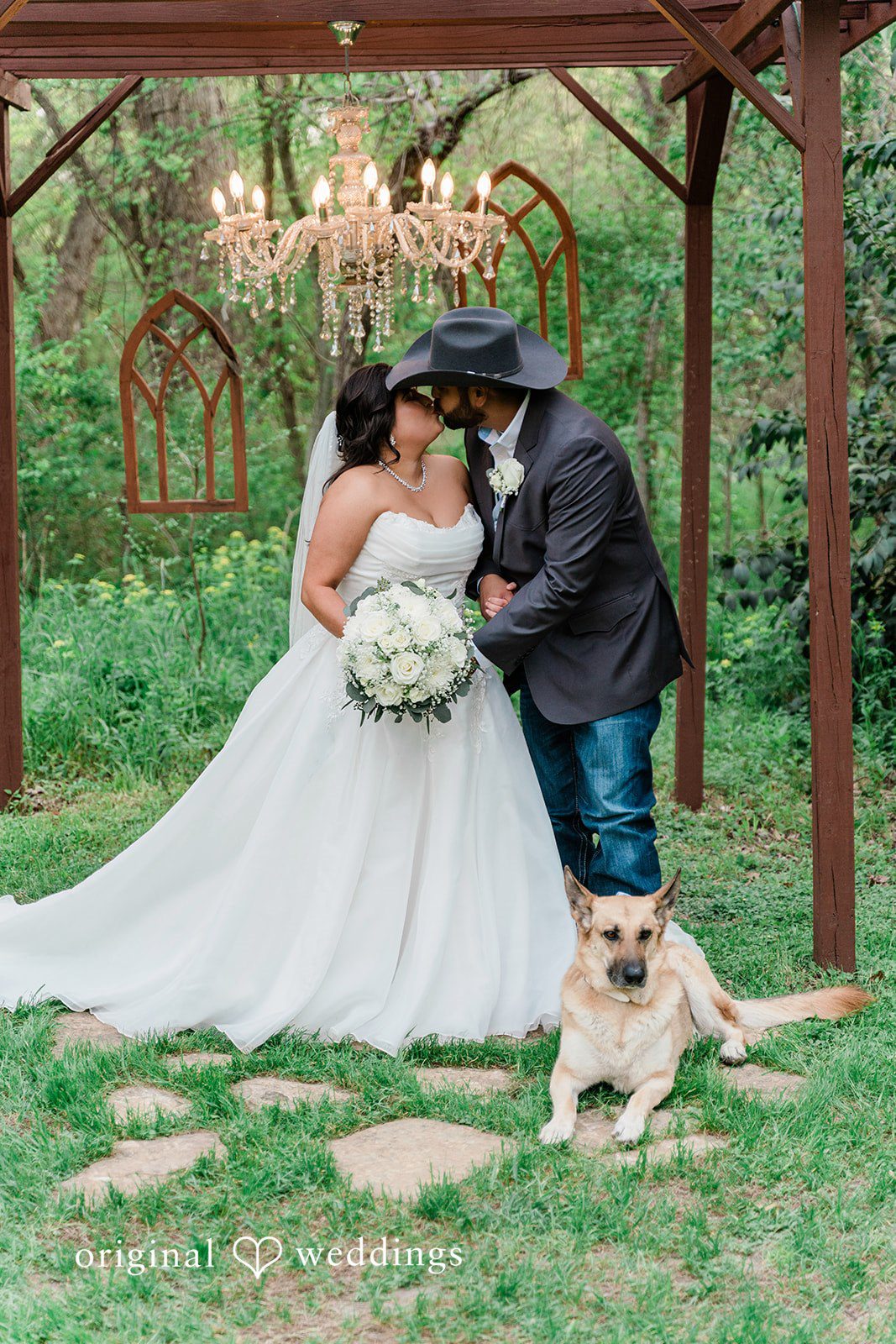 The couple shares a romantic kiss by the arbor