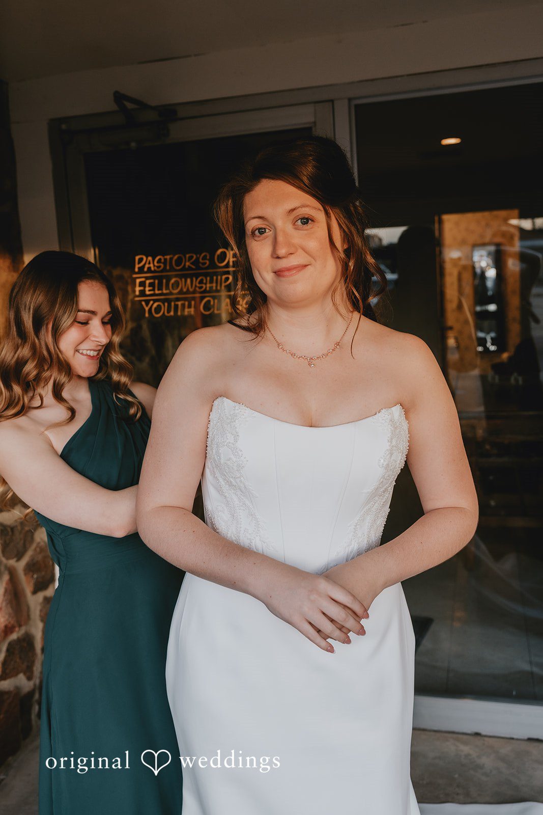 Bridesmaid helping bride get ready before Bethel Baptist Church wedding ceremony