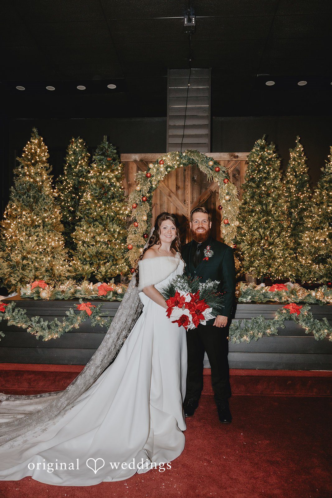 Bride and groom posing together in front of Christmas trees and festive decor