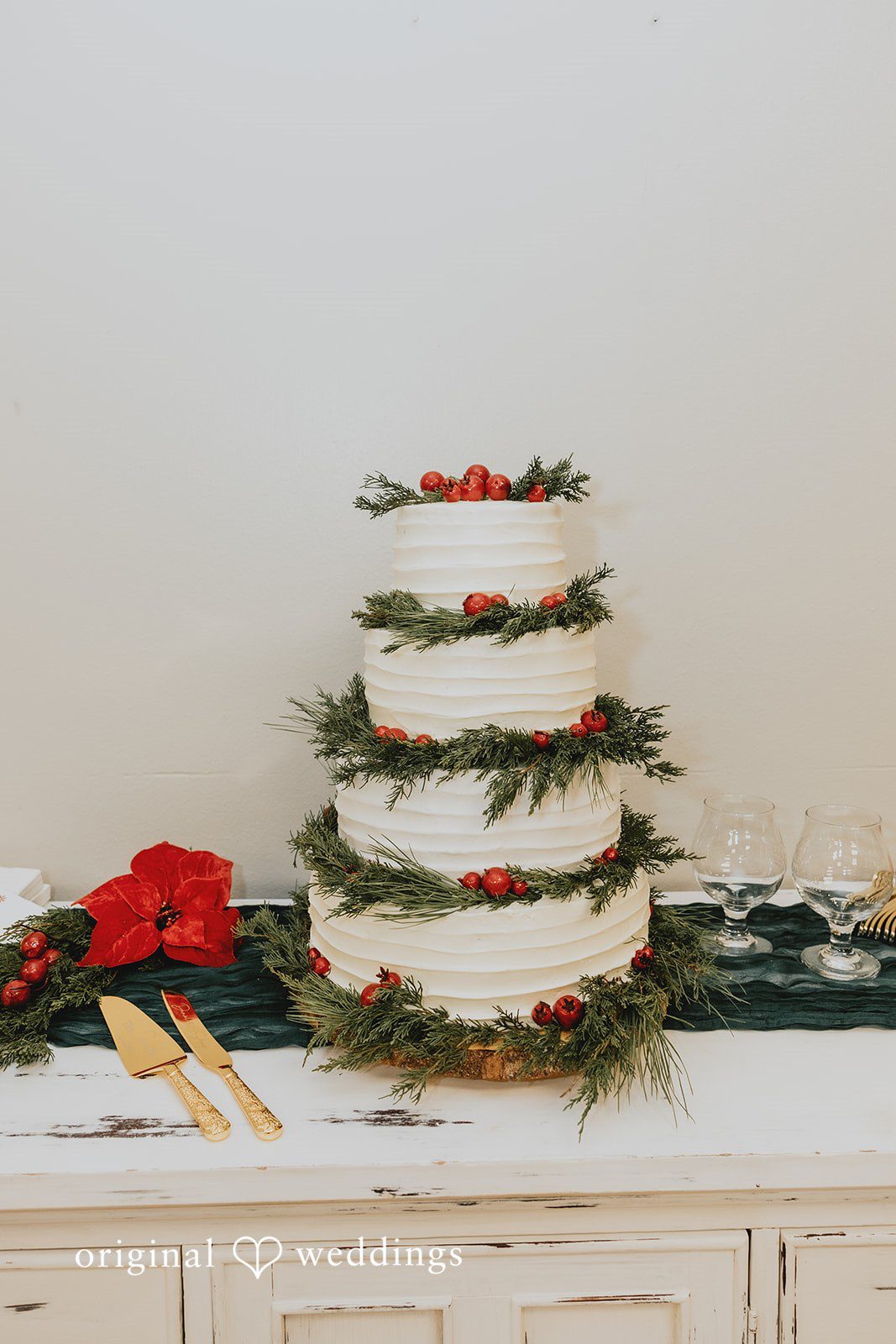 Elegant Christmas wedding cake decorated with greenery and red holiday berries