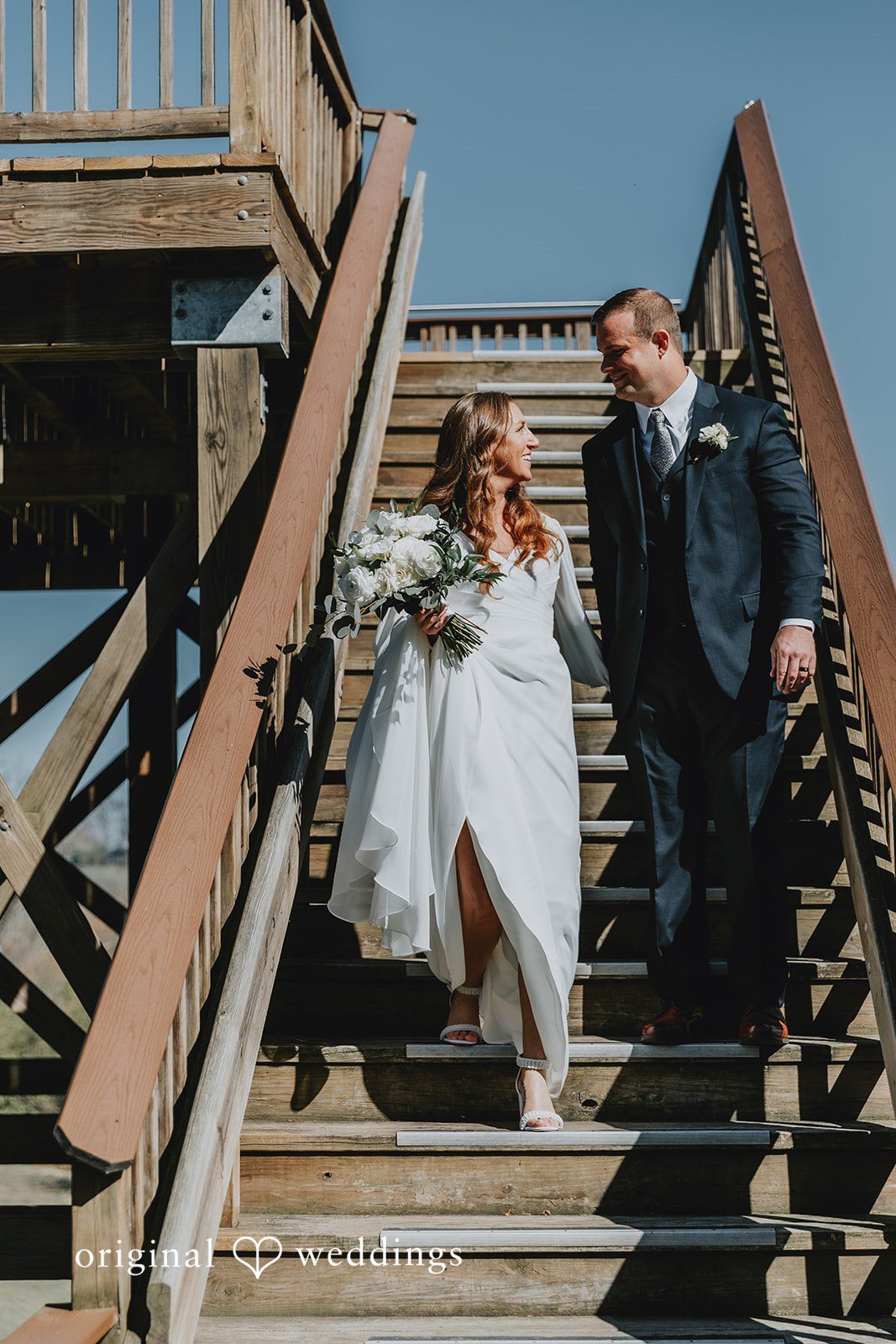 Bride and groom walking down outdoor stairs together