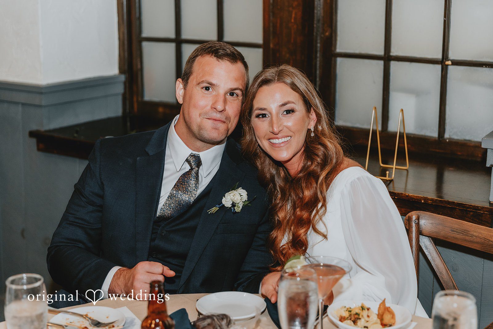 Bride and groom smiling together at the reception table