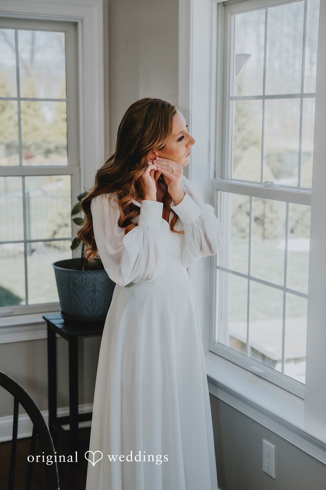 Bride getting ready by the window in soft natural light