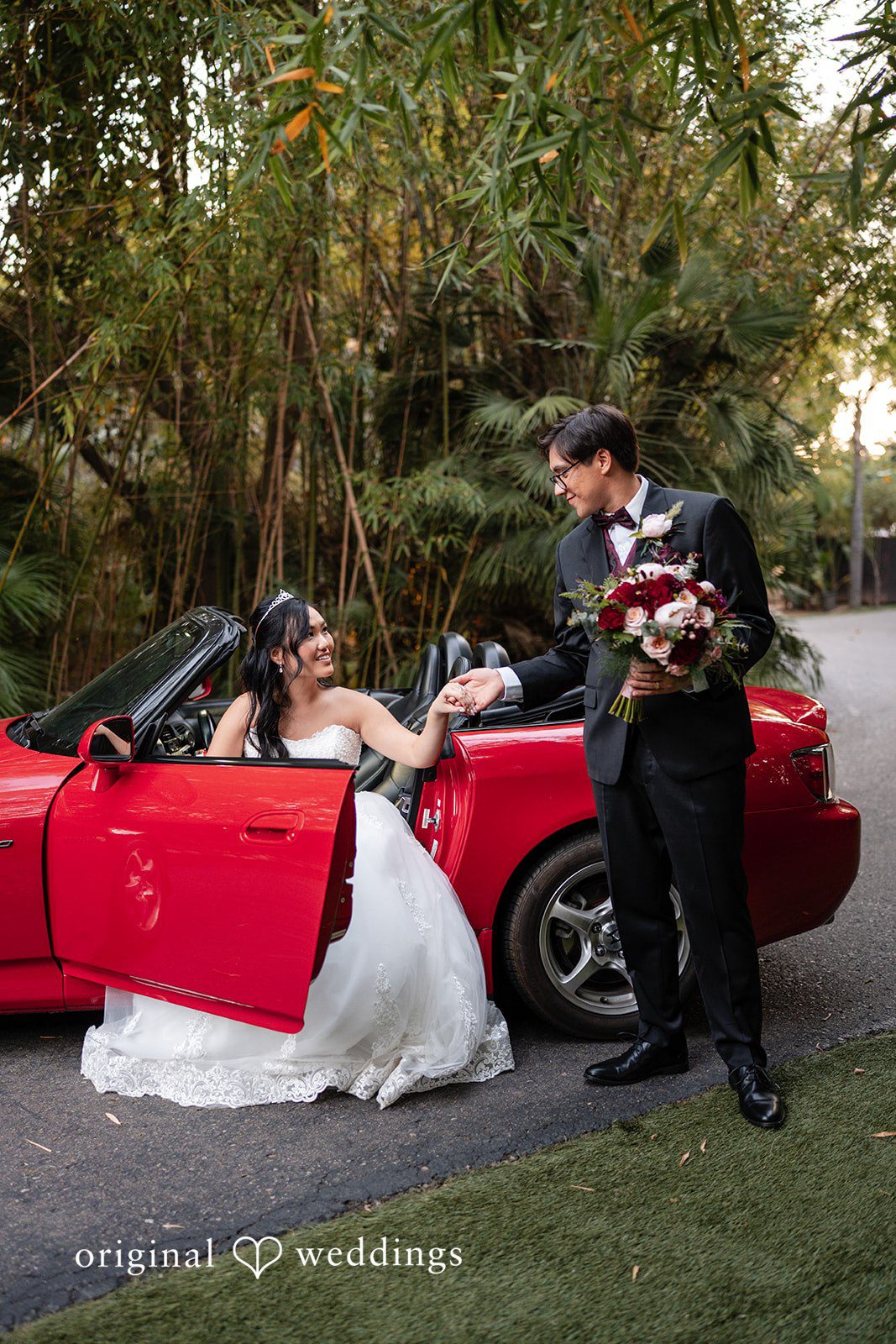 A stylish portrait of the couple by their red car