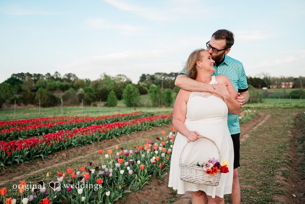 A couple embracing in a tulip field during golden hour by a DC engagement photographer.