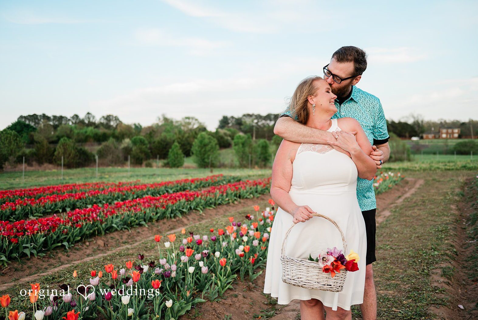 A couple embracing in a tulip field during golden hour by a DC engagement photographer.