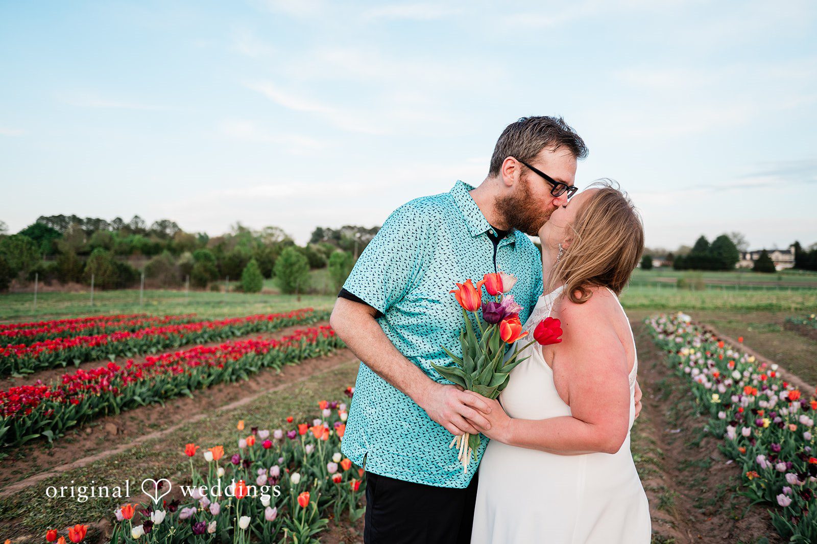Suzanna + Morgan Tender kiss captured between tulips at Burnside Farms engagement session
