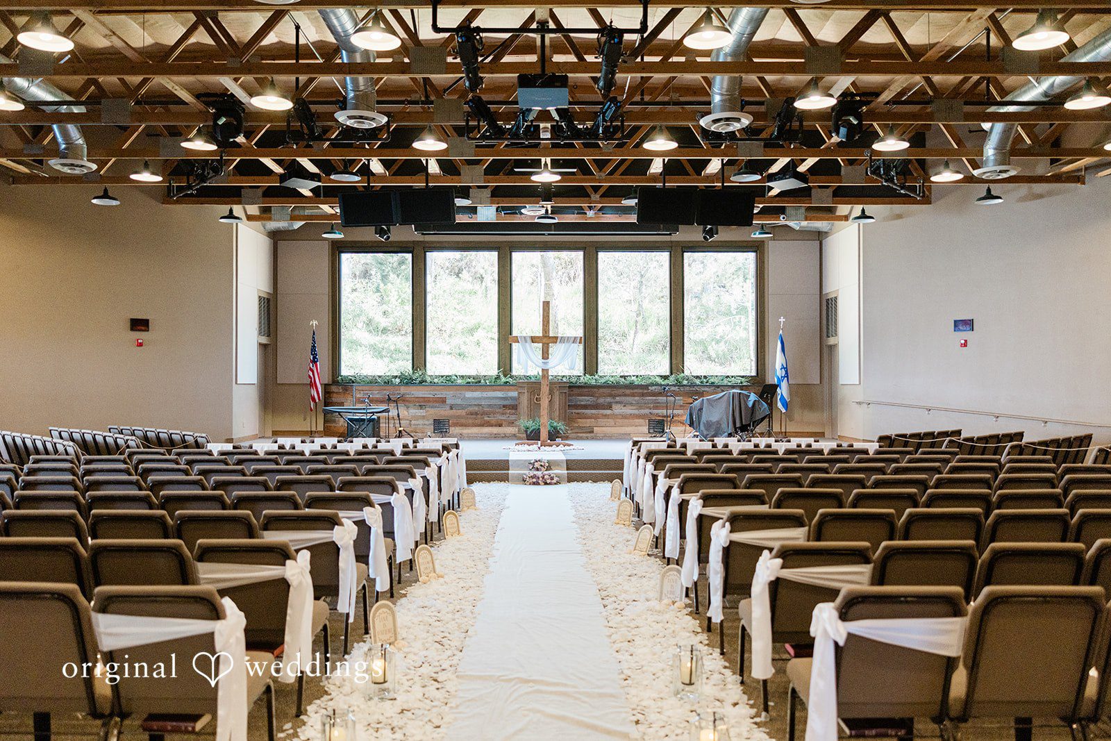 Wedding ceremony venue with empty wooden chairs facing an altar and a center aisle.