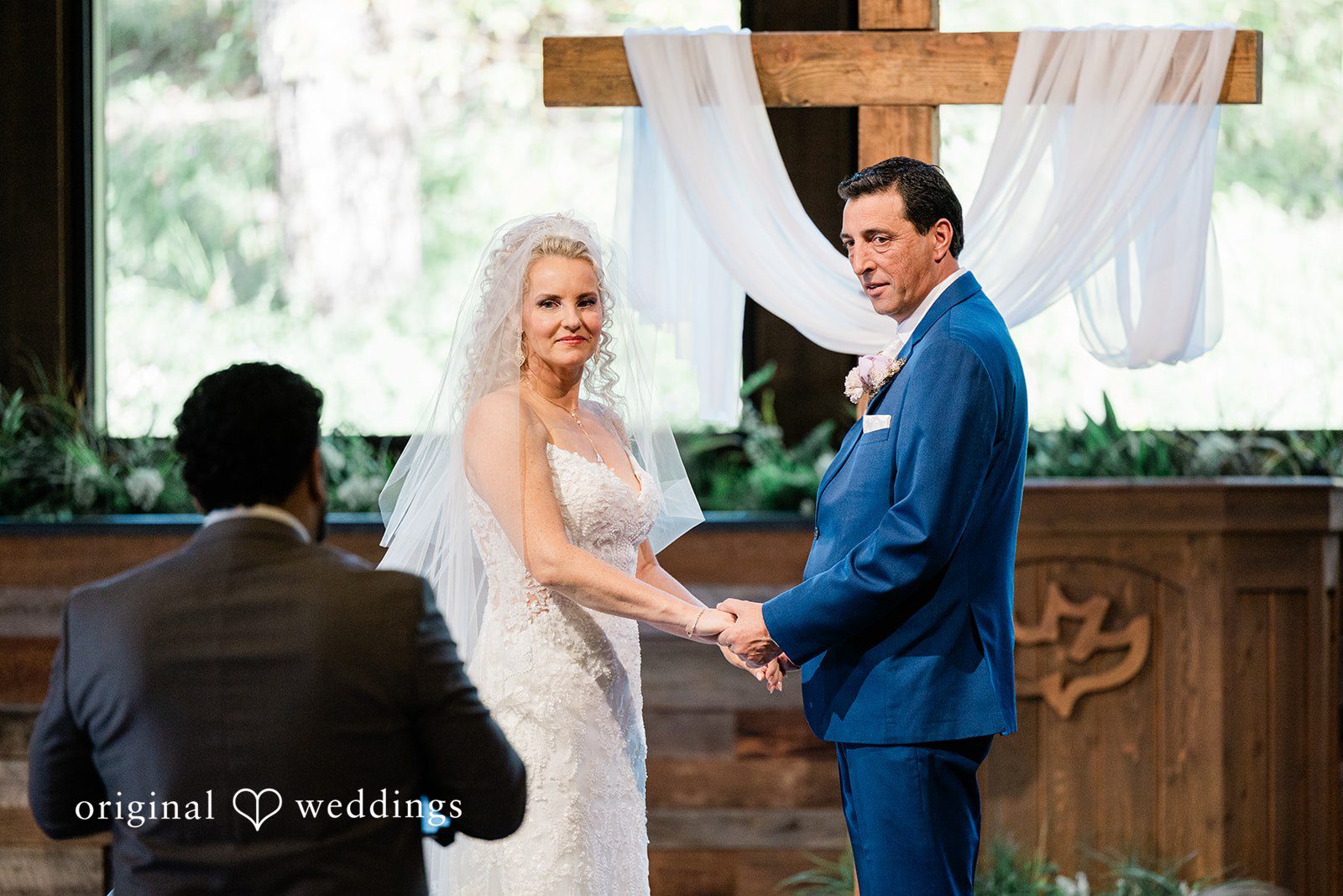 Bride and groom holding hands at the altar during their wedding ceremony at Calvary Chapel Bible Fellowship