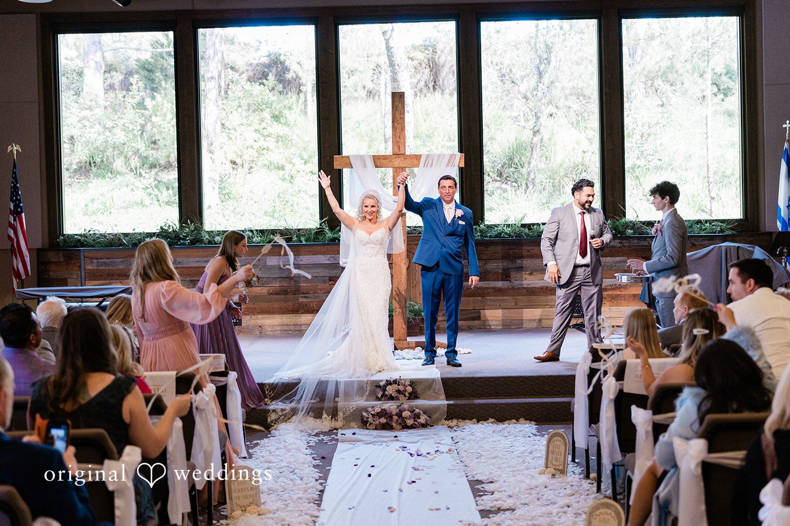 Newlyweds walking back down the aisle together as guests cheer.