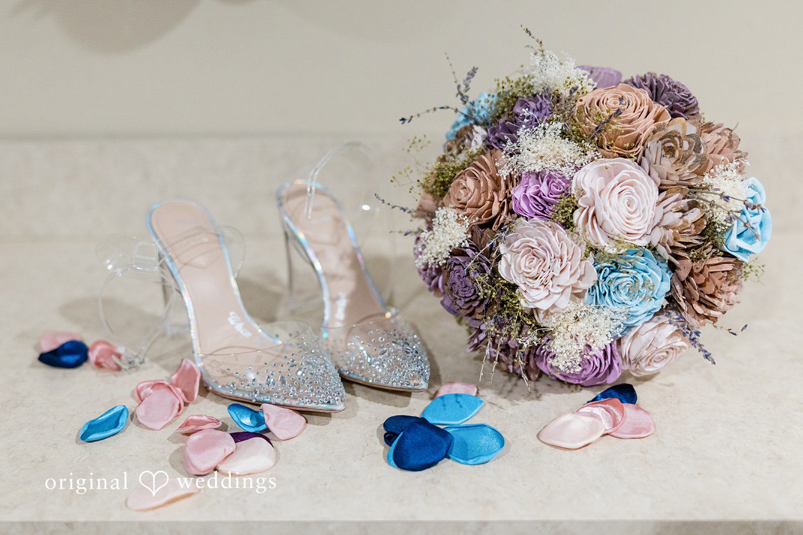 Bridal details including a floral bouquet, silver high heels, and scattered blue petals.