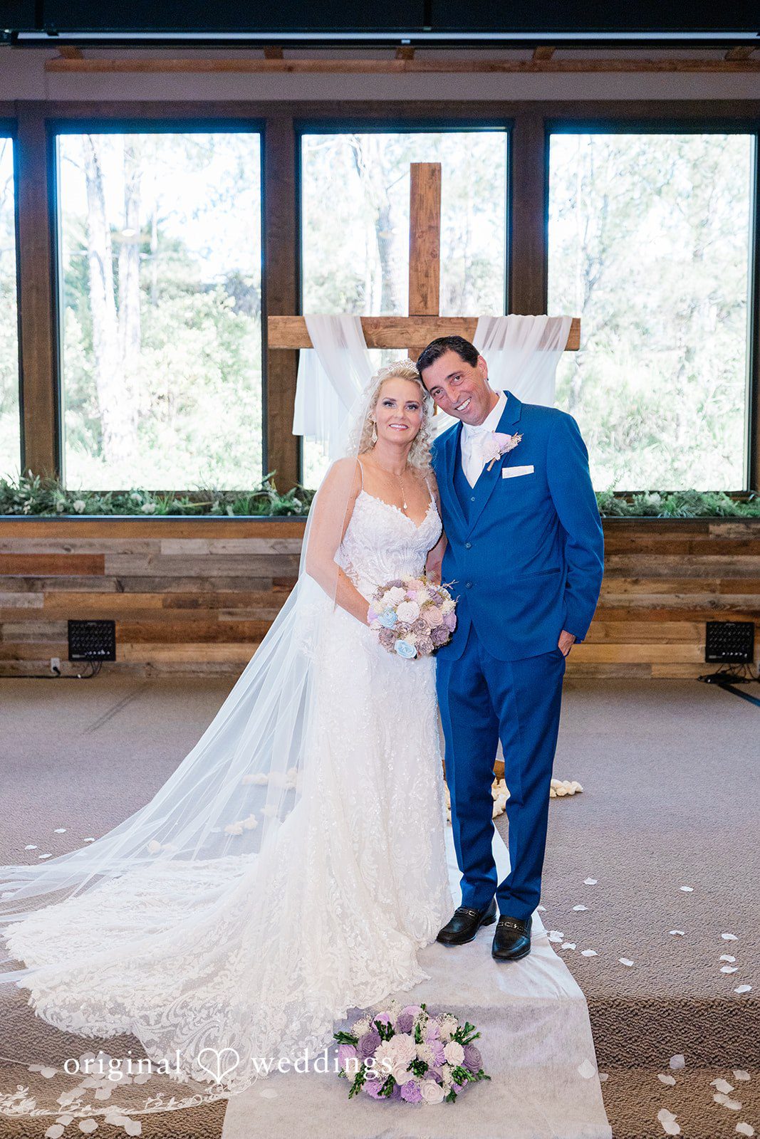 Couple posing together at the altar in front of a wooden cross.