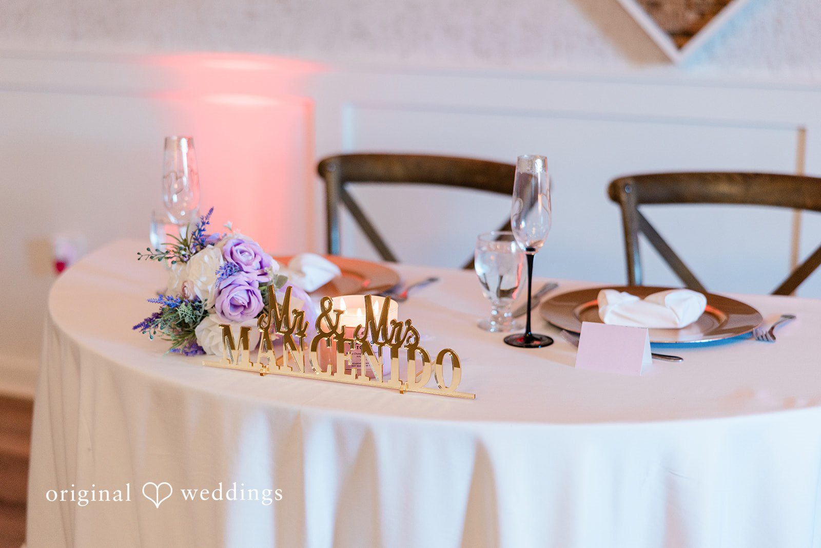 Close-up of a sweetheart table decorated with candles and greenery.