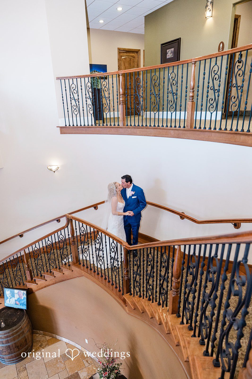 Couple kissing on a grand wooden staircase.