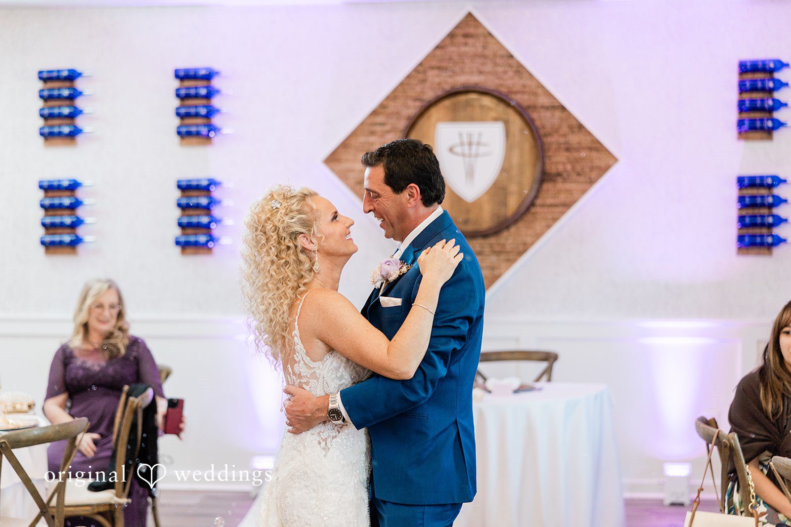 Bride and groom sharing a dance together in front of a decorative wall display.