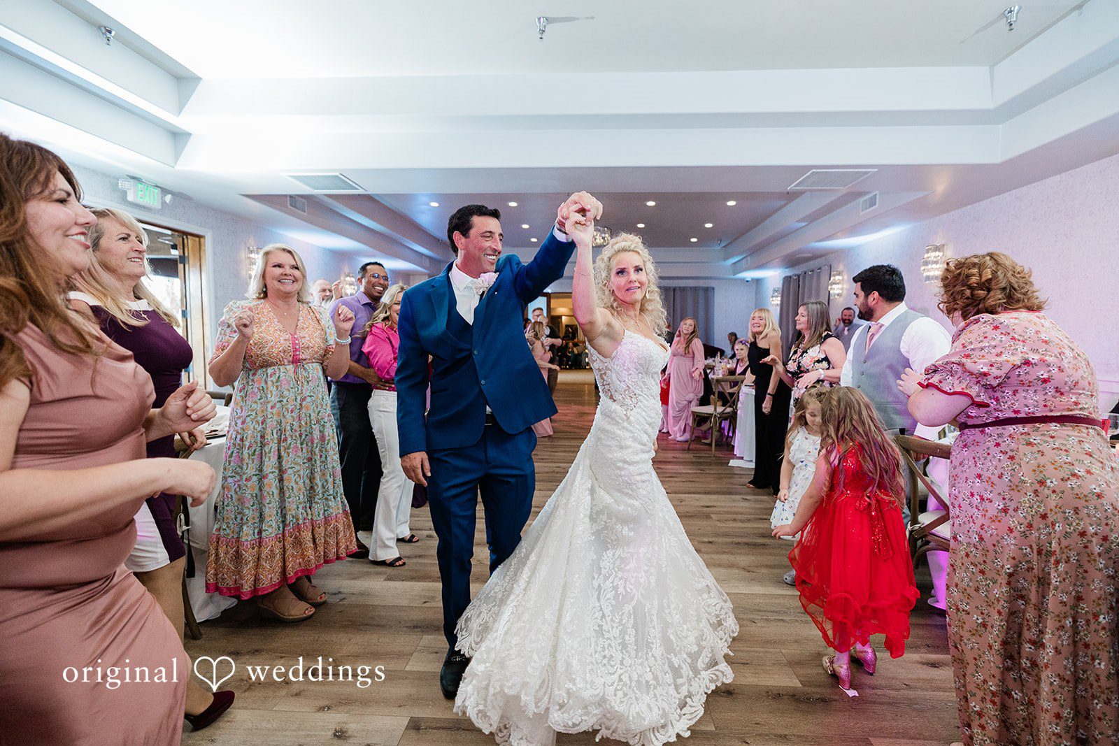 Bride and groom dancing surrounded by guests on the dance floor.