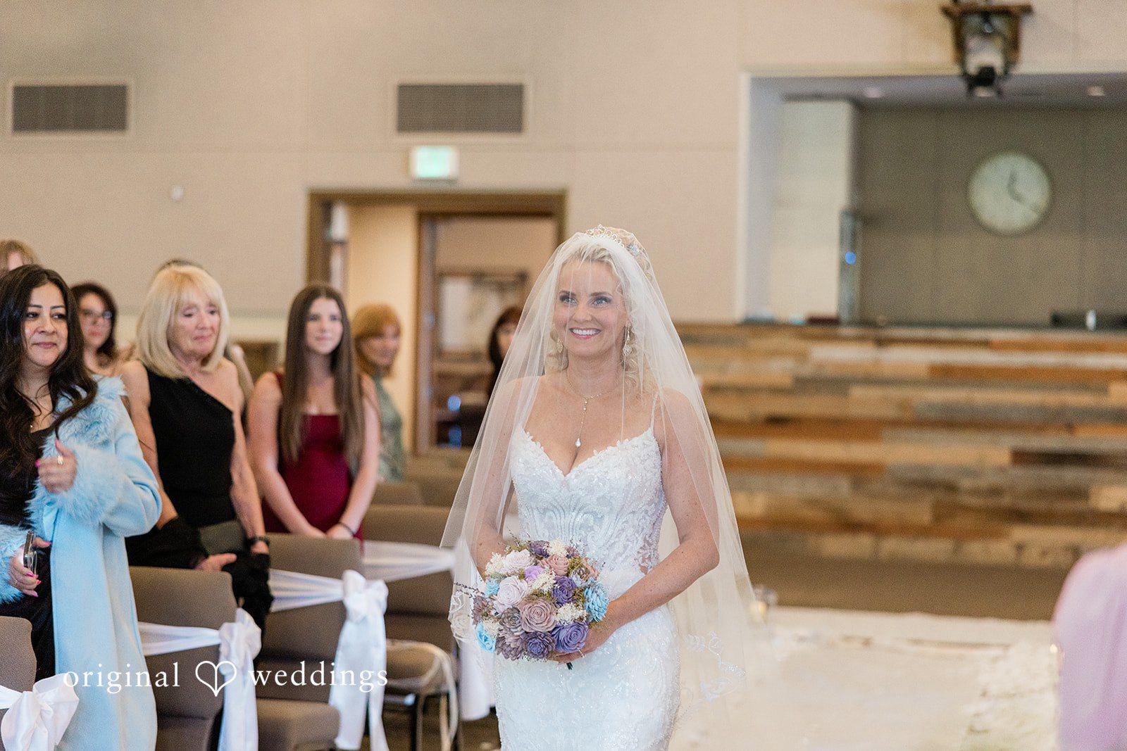 Bride in a white gown and veil walking down the aisle during the ceremony.