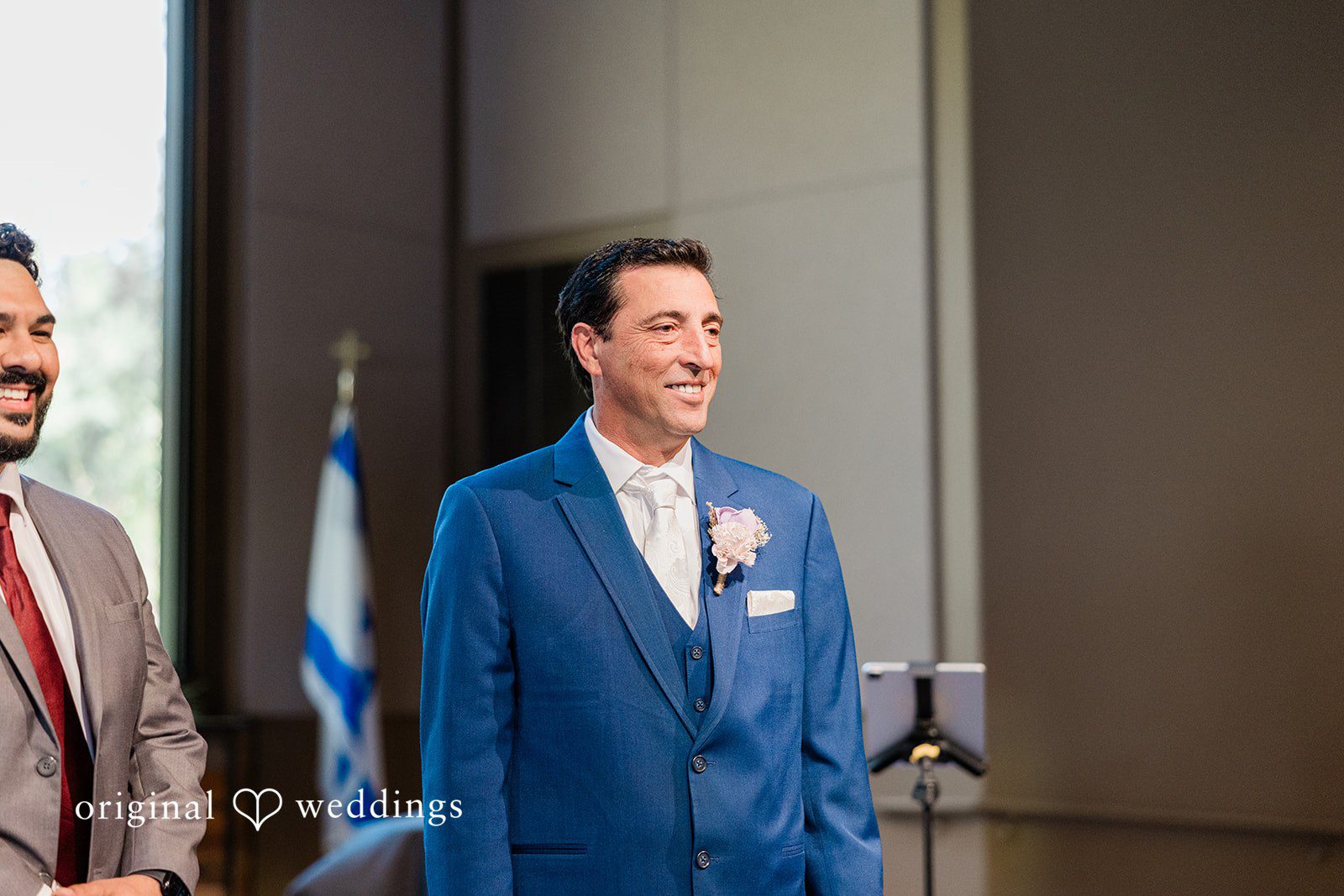 Smiling groom dressed in a bright blue suit standing at the altar.