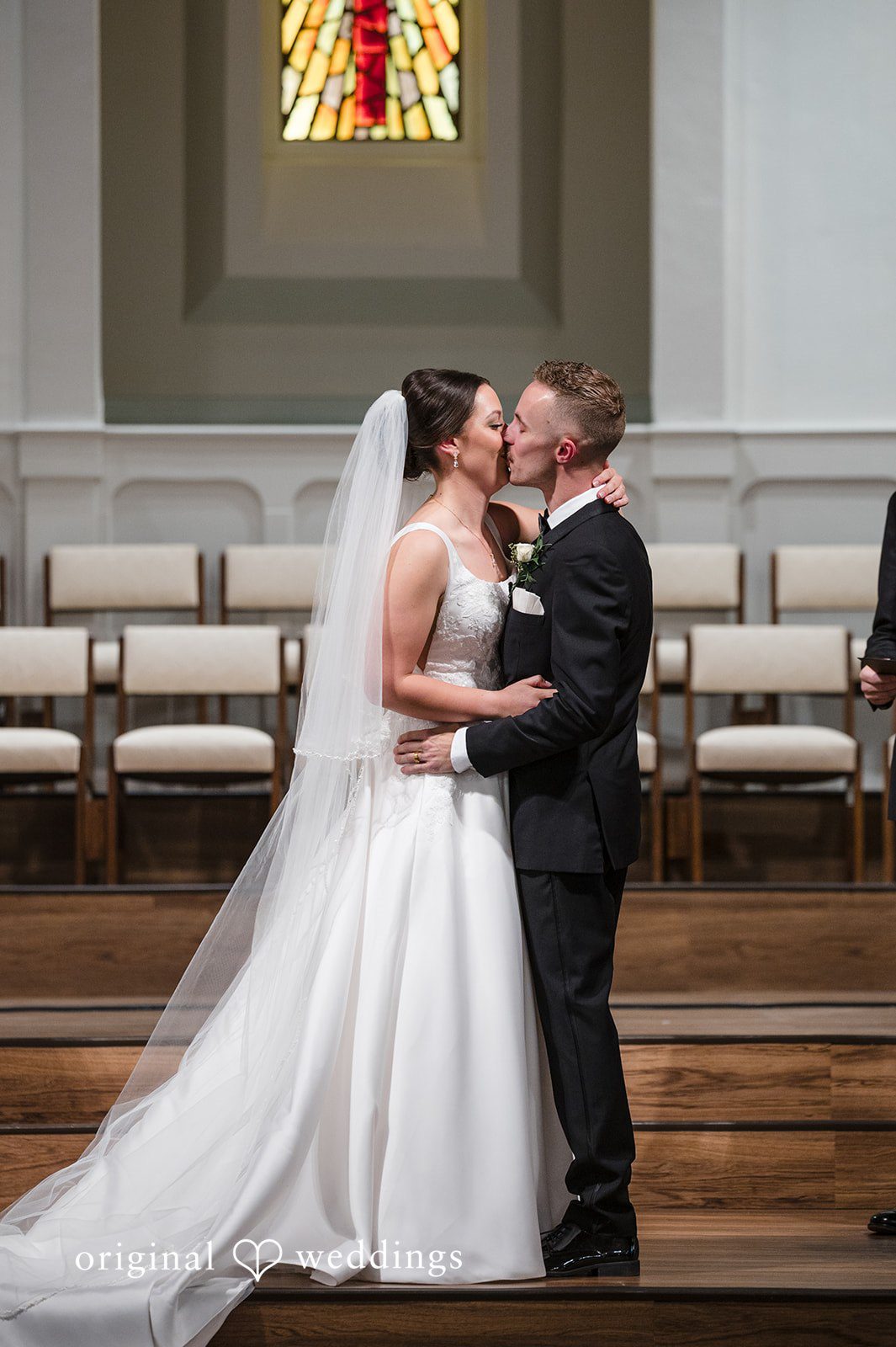 Newly married couple sharing a beautiful kiss inside the elegant church ceremony space
