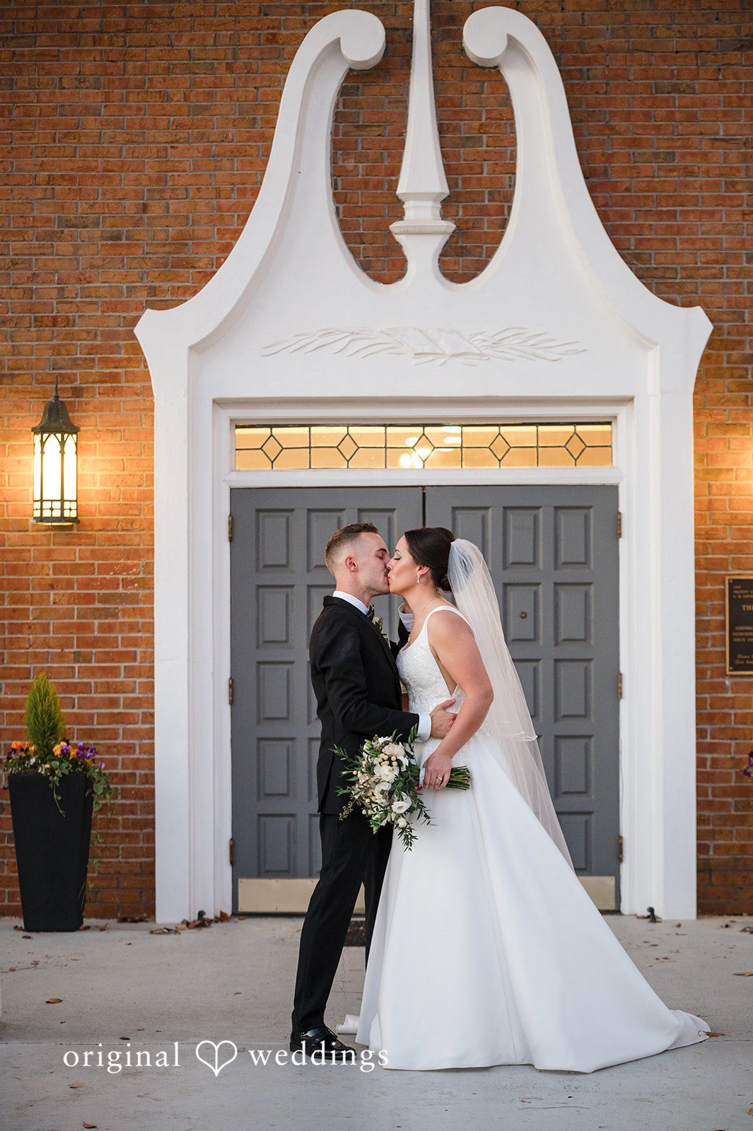 Bride and groom sharing a romantic kiss outside