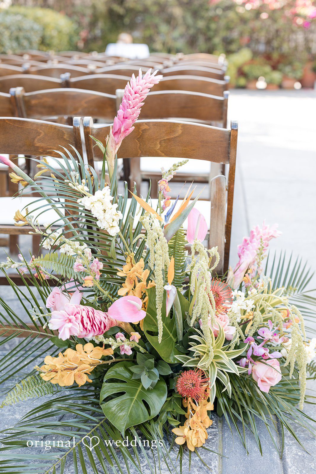 Vibrant tropical floral arrangement featuring pink flowers and green palm leaves.