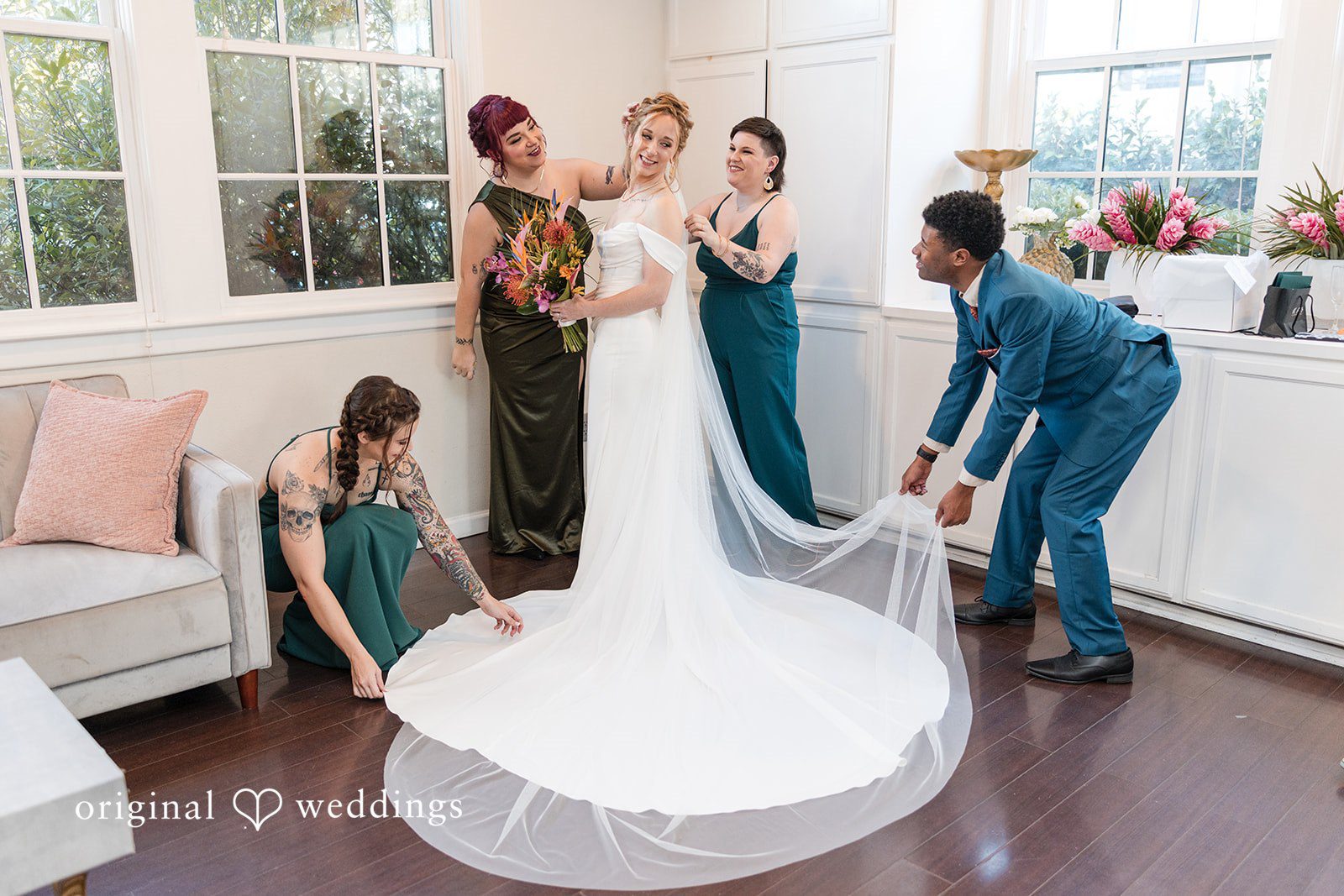 Group of bridesmaids and assistants arranging a bride's long train and veil.