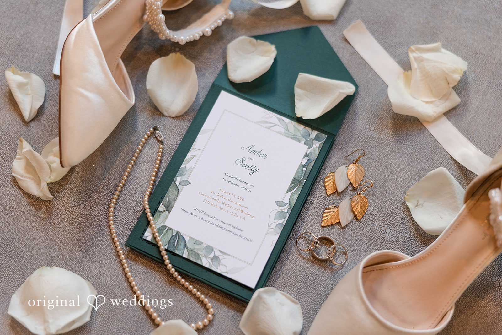 Flat lay composition of a wedding invitation, bridal heels, and flower petals.