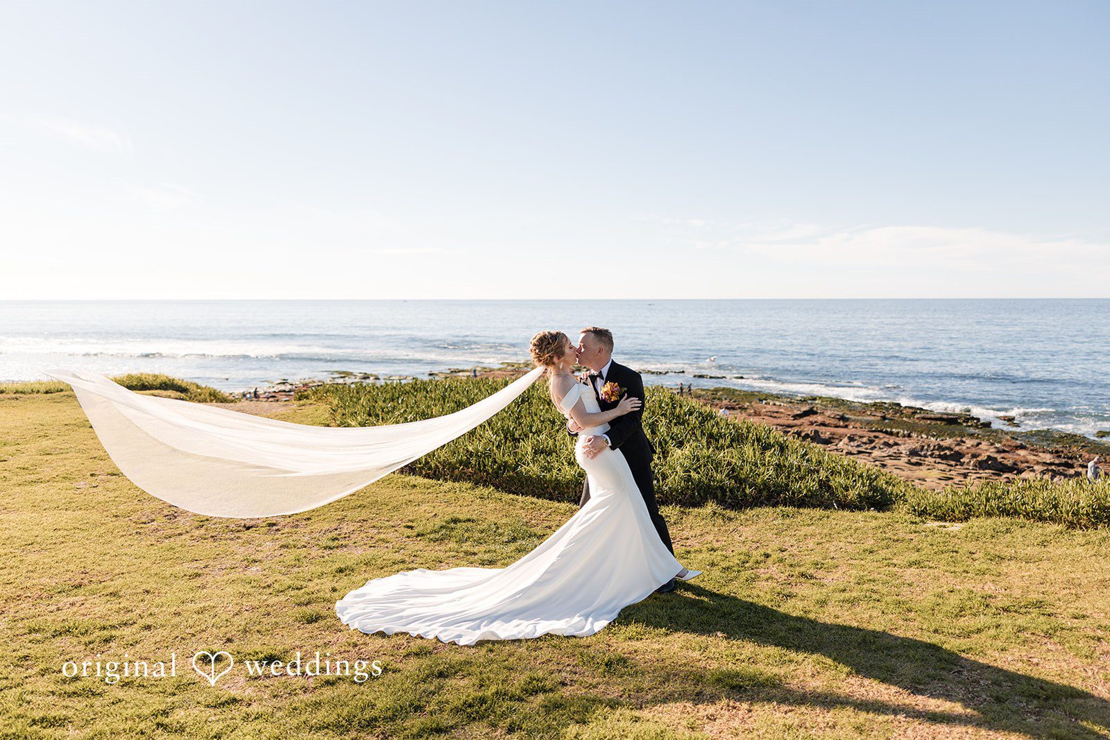 Bride and groom kissing with a blowing veil.