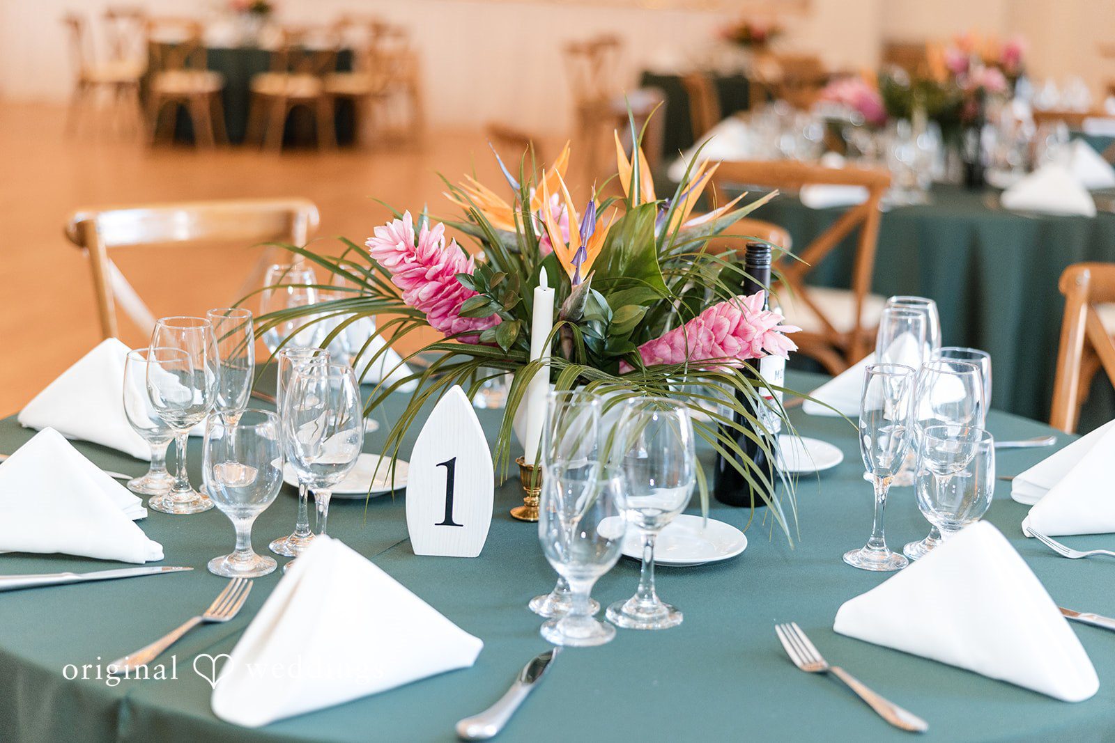 Close-up of a table setting with white napkins, glassware, and a colorful floral centerpiece.