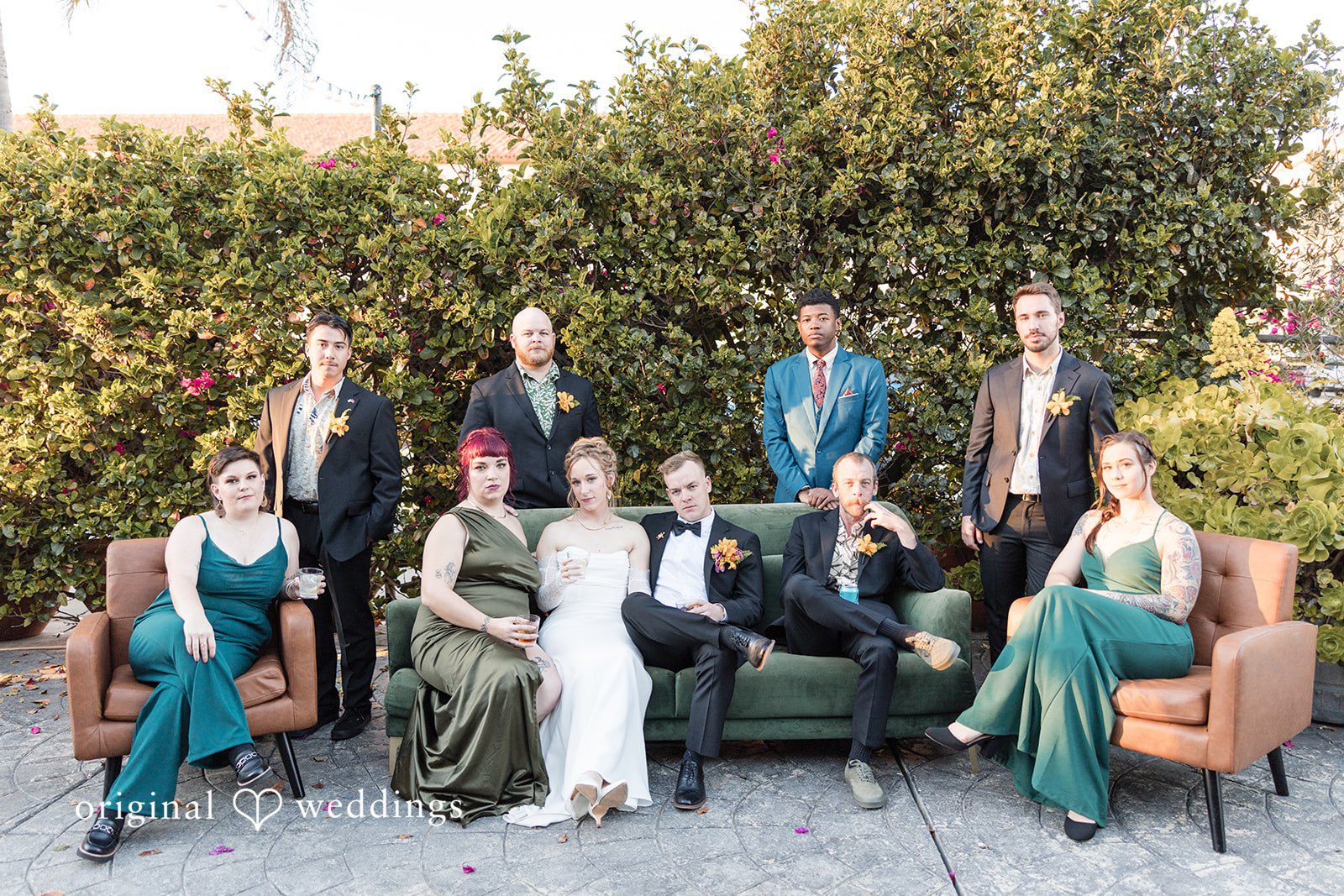 Wedding party posing together around a green couch.