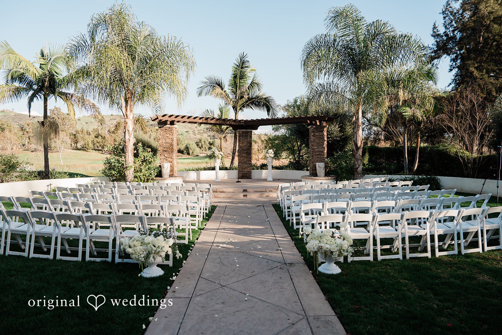 Jinelle + Brett San Diego Wedding Photography by Original Weddings capturing elegant outdoor wedding ceremony setup with white chairs and palm trees at Fallbrook Estate