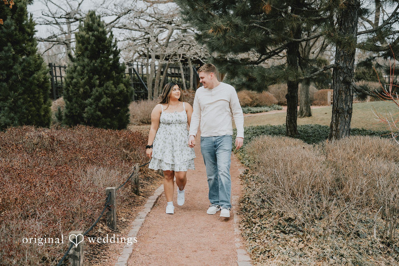 Couple holding hands while walking on a narrow path.