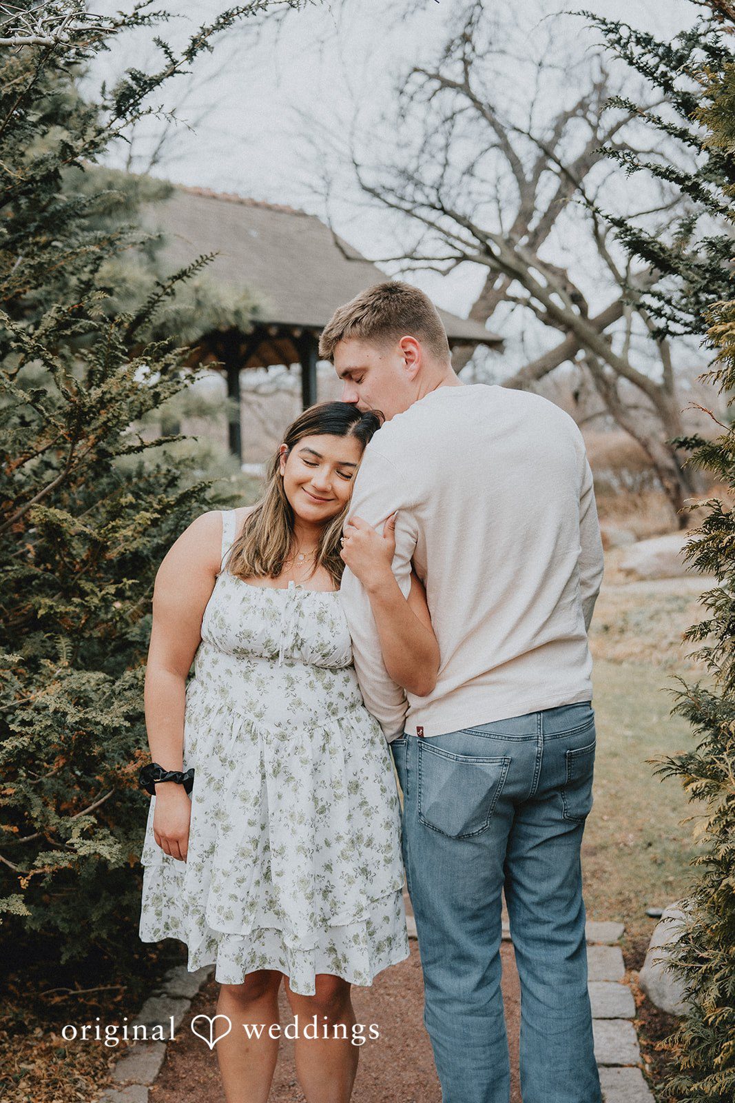 Leaning head on a shoulder while standing on a stone path.