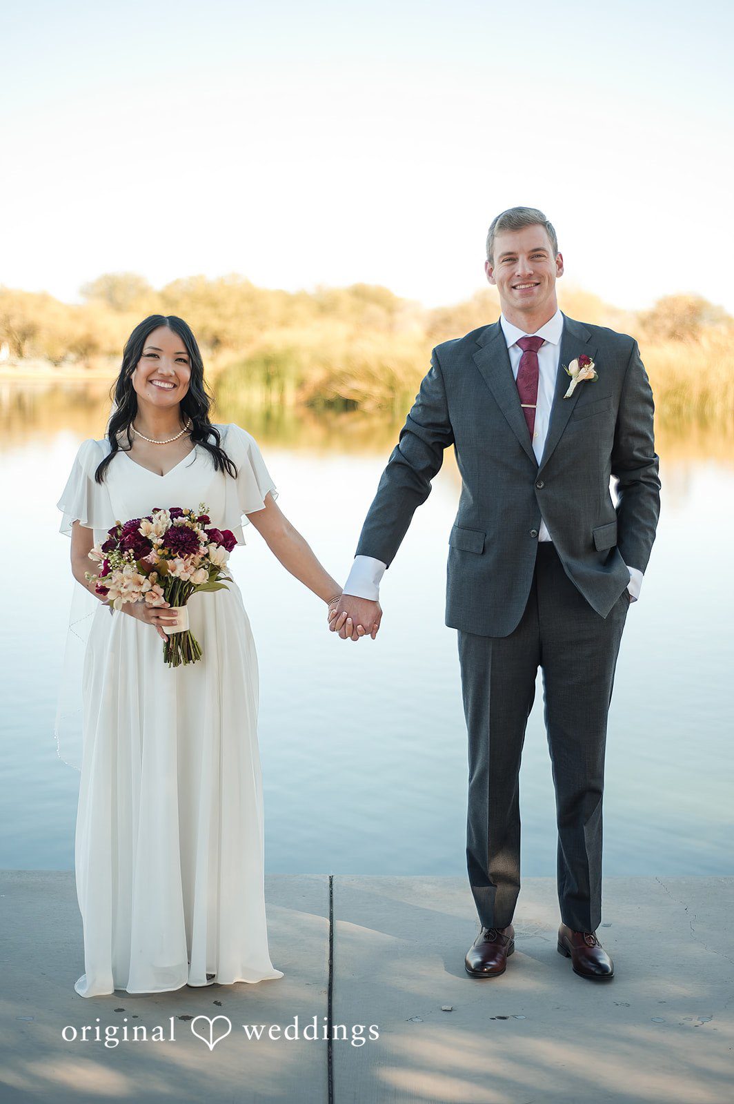 Bride and groom holding hands with the lake in the background